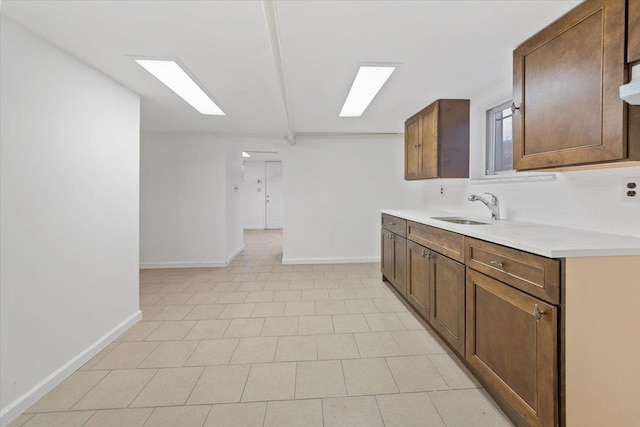 1856 Edison Ave, Bronx, NY 10461 - kitchen featuring a sink, baseboards, light countertops, tasteful backsplash, and arched walkways