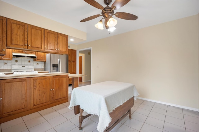 7 Mailler Ave, Cornwall, NY 12518 - kitchen featuring gas range gas stove, under cabinet range hood, brown cabinets, stainless steel refrigerator with ice dispenser, and decorative backsplash