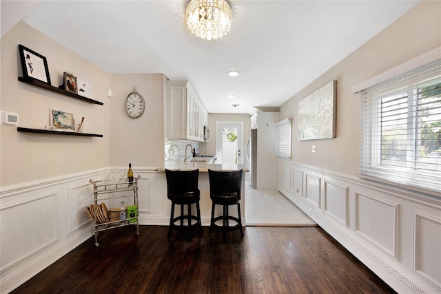 651 Hyman Ave, Bay Shore, NY 11706 - kitchen with healthy amount of natural light, light countertops, a decorative wall, a chandelier, and wood finished floors