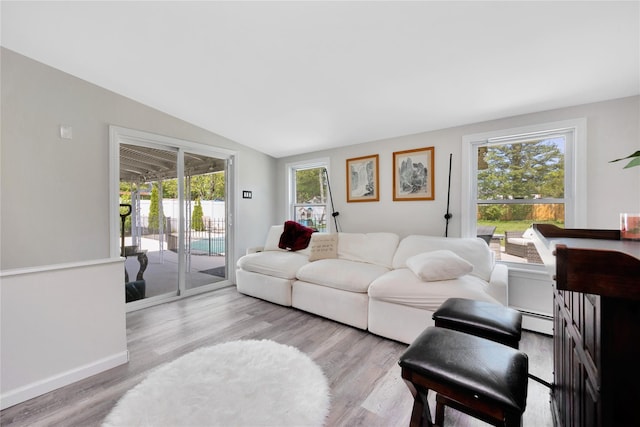 651 Hyman Ave, Bay Shore, NY 11706 - living room featuring baseboard heating, wood finished floors, vaulted ceiling, and baseboards