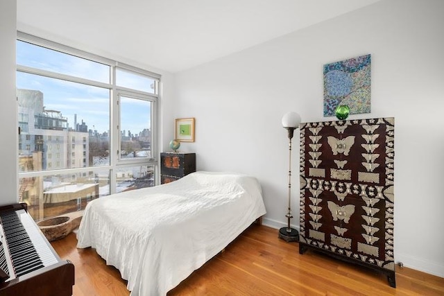 11-24 31st Ave Unit 5E, Astoria, NY 11106 - bedroom featuring wood finished floors, a view of city, and baseboards