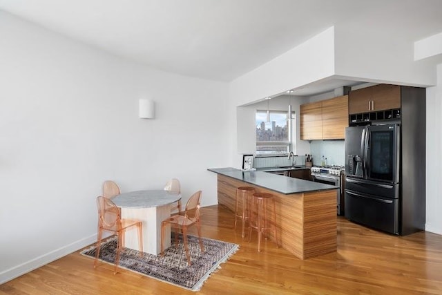 11-24 31st Ave Unit 5E, Astoria, NY 11106 - kitchen featuring smart refrigerator, a peninsula, a breakfast bar area, dark countertops, and a sink