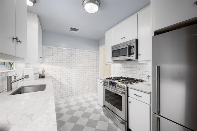 3 Reigate Pl, Suffern, NY 10901 - kitchen featuring appliances with stainless steel finishes, a sink, white cabinets, light stone countertops, and tasteful backsplash