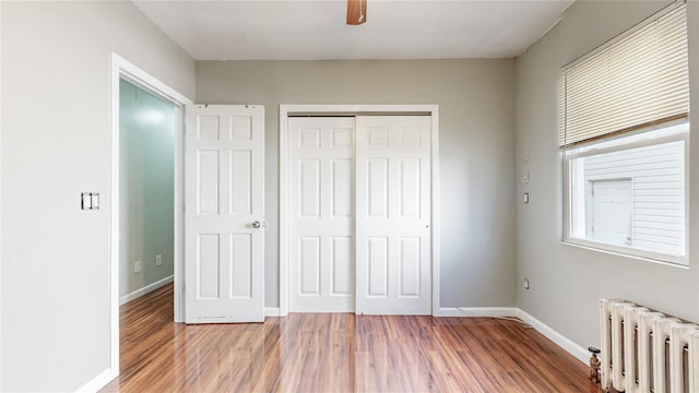 105 Pilgrim Pl, Valley Stream, NY 11580 - unfurnished bedroom with radiator, wood finished floors, a closet, and baseboards
