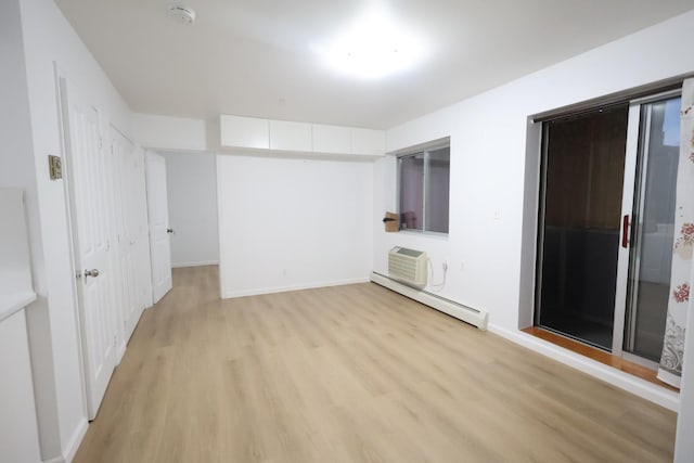 140-37 Cherry Unit 5C, Flushing, NY 11355 - spare room featuring baseboard heating, light wood-style flooring, a wall mounted air conditioner, and baseboards