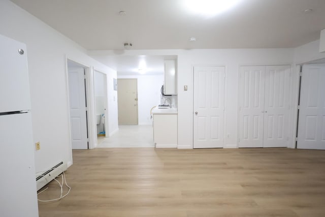 140-37 Cherry Unit 5C, Flushing, NY 11355 - basement with freestanding refrigerator, baseboard heating, light wood-type flooring, and baseboards