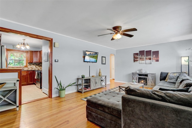 77 N Prospect Ave, Patchogue, NY 11772 - living room featuring a glass covered fireplace, a chandelier, ceiling fan, light wood-style floors, and arched walkways