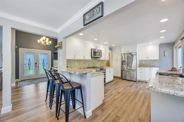 5 Firwood Dr, Farmingville, NY 11738 - kitchen featuring stainless steel appliances, a peninsula, a chandelier, white cabinets, and crown molding