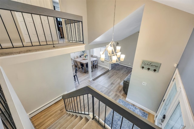 5 Firwood Dr, Farmingville, NY 11738 - stairway featuring a chandelier, wood finished floors, a baseboard heating unit, a high ceiling, and baseboards