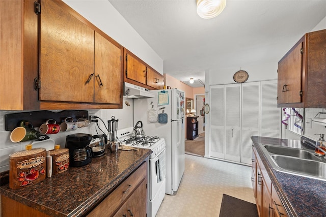 397 Mine Rd, Monroe, NY 10950 - kitchen with white range with gas cooktop, a sink, under cabinet range hood, dark countertops, and brown cabinets