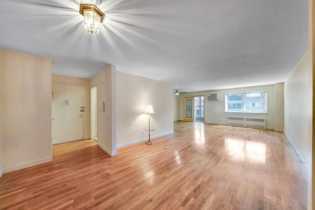 100 Lincoln Ave Unit 28C, Mineola, NY 11501 - unfurnished living room with radiator heating unit, light wood-style flooring, a wall mounted air conditioner, and baseboards