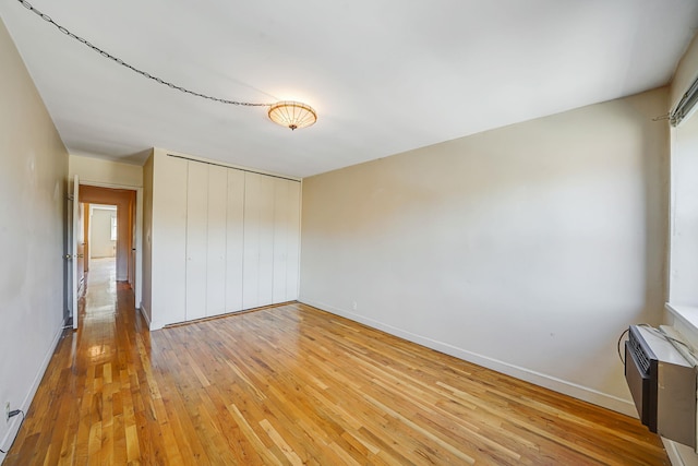 100 Lincoln Ave Unit 28C, Mineola, NY 11501 - unfurnished bedroom featuring light wood-type flooring, baseboards, a wall mounted AC, and a closet