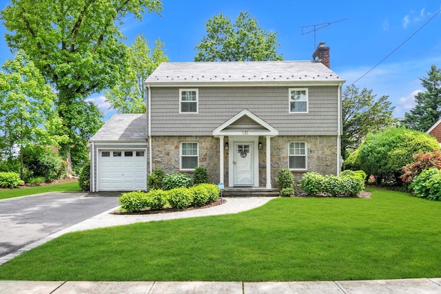 131 Charles St, East Williston, NY 11596 - colonial inspired home featuring stone siding, driveway, a chimney, an attached garage, and a front lawn