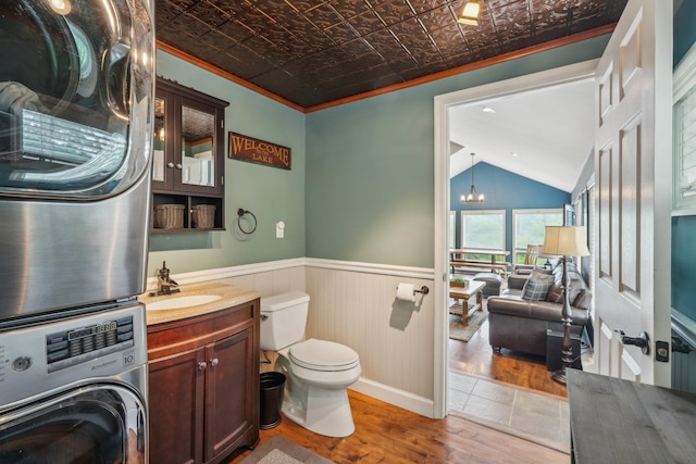 49 Brook Trl, Greenwood Lake, NY 10925 - bathroom featuring wood finished floors, stacked washer and clothes dryer, toilet, ornamental molding, and an ornate ceiling
