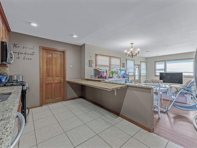 4 Whitebirch Ln, Commack, NY 11725 - kitchen featuring stainless steel appliances, a chandelier, light stone counters, a peninsula, and light tile patterned floors
