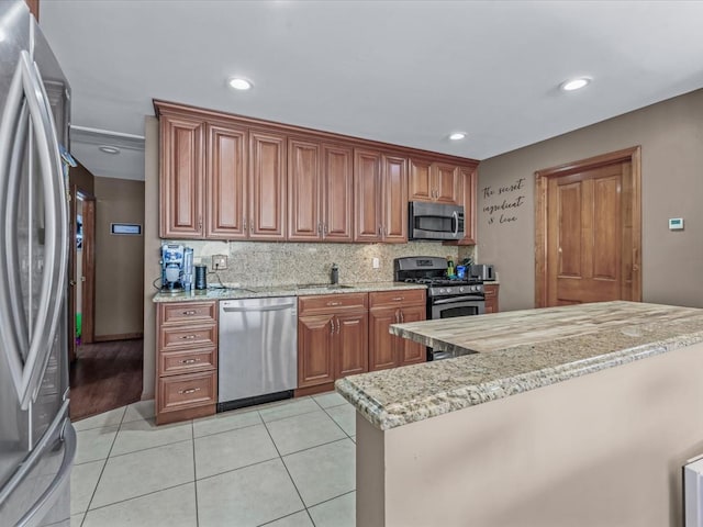 4 Whitebirch Ln, Commack, NY 11725 - kitchen featuring appliances with stainless steel finishes, light stone counters, backsplash, brown cabinetry, and light tile patterned flooring