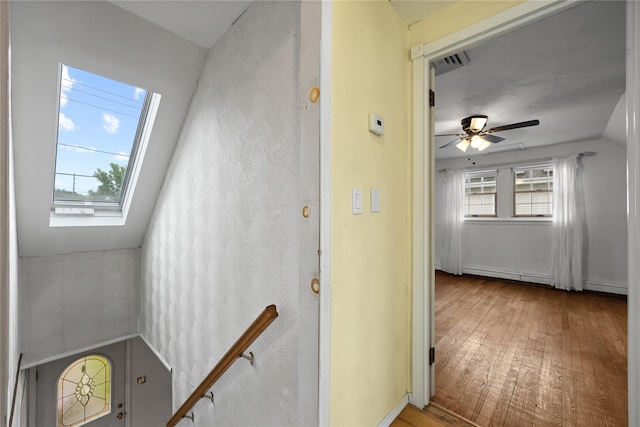 21 Arizona Ave, Syosset, NY 11791 - staircase featuring wood finished floors, vaulted ceiling, a skylight, a baseboard heating unit, and ceiling fan