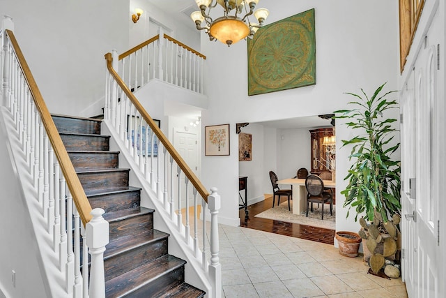 1138 Carlls Straight Path, Dix Hills, NY 11746 - stairs featuring tile patterned flooring, a chandelier, a high ceiling, and baseboards