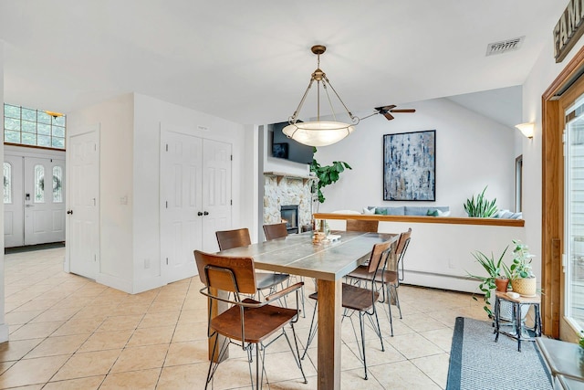 1138 Carlls Straight Path, Dix Hills, NY 11746 - dining room with a baseboard heating unit, light tile patterned floors, a stone fireplace, ceiling fan, and baseboards