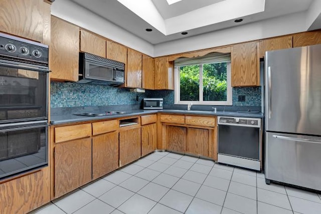 10 Lisa Dr, Northport, NY 11768 - kitchen with black appliances, a skylight, tasteful backsplash, light tile patterned flooring, and brown cabinetry