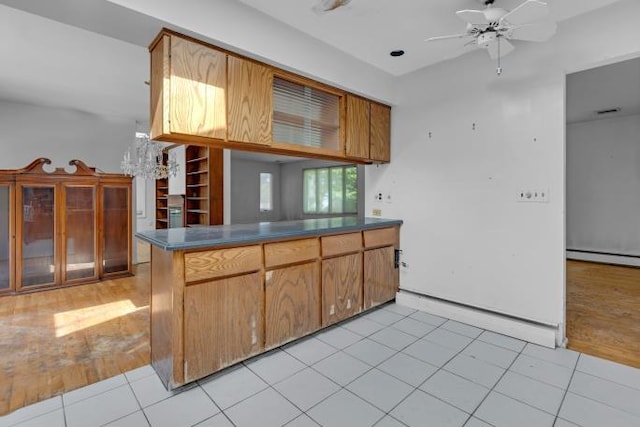 10 Lisa Dr, Northport, NY 11768 - kitchen with dark countertops, ceiling fan, light tile patterned floors, a baseboard heating unit, and brown cabinetry