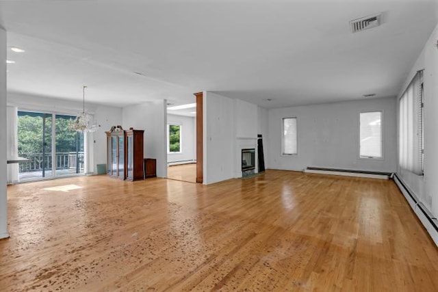 10 Lisa Dr, Northport, NY 11768 - unfurnished living room with a chandelier, light wood-type flooring, baseboard heating, a glass covered fireplace, and a baseboard heating unit