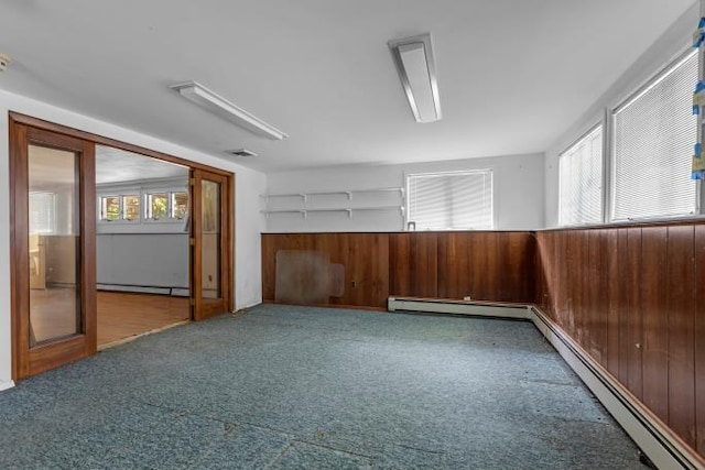 10 Lisa Dr, Northport, NY 11768 - spare room featuring healthy amount of natural light, carpet flooring, a baseboard radiator, and wooden walls