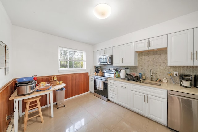 19 Decker Dr, Washingtonville, NY 10992 - kitchen featuring appliances with stainless steel finishes, a sink, light countertops, white cabinetry, and wainscoting