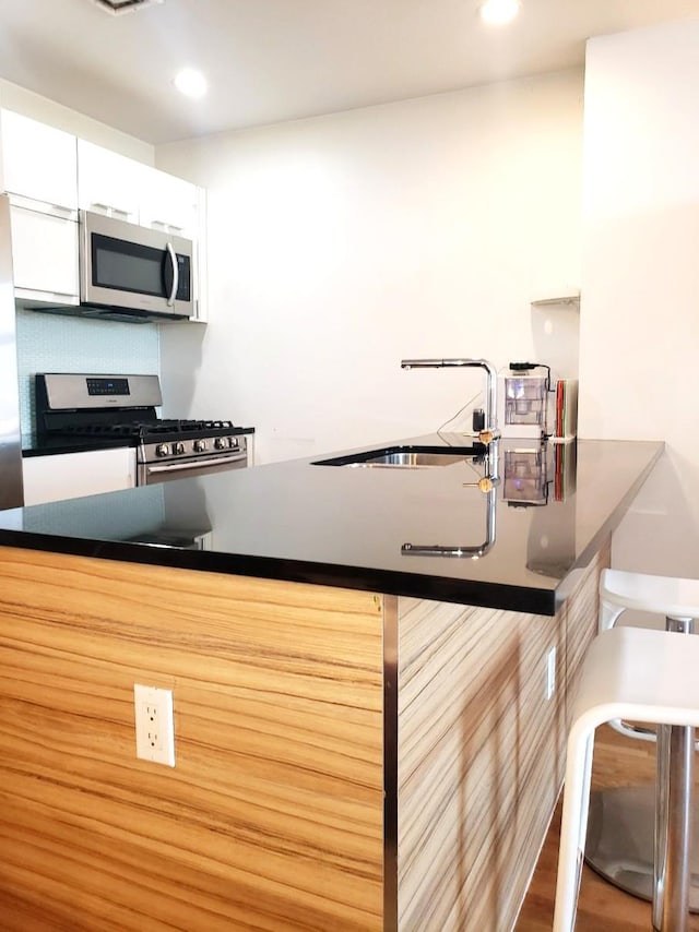 2311 21st Ave Unit 3C, Astoria, NY 11105 - kitchen with appliances with stainless steel finishes, a sink, white cabinetry, recessed lighting, and decorative backsplash