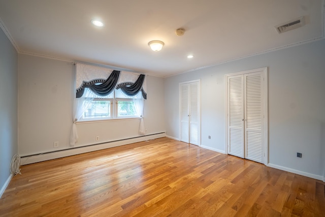 5 Forest Rd, Valley Stream, NY 11581 - unfurnished bedroom with two closets, a baseboard heating unit, ornamental molding, wood finished floors, and baseboards