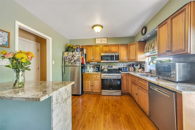 1623 Washington Ave, Bohemia, NY 11716 - kitchen with stainless steel appliances, a sink, light wood finished floors, brown cabinets, and decorative backsplash
