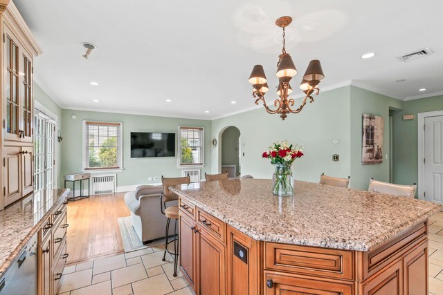 74 Buckingham Rd, West Hempstead, NY 11552 - kitchen with radiator heating unit, arched walkways, recessed lighting, brown cabinets, and light stone countertops
