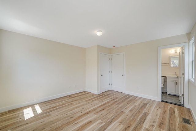 2939 N Wading River Rd, Wading River, NY 11792 - unfurnished bedroom featuring light wood-style flooring, baseboards, connected bathroom, and a sink