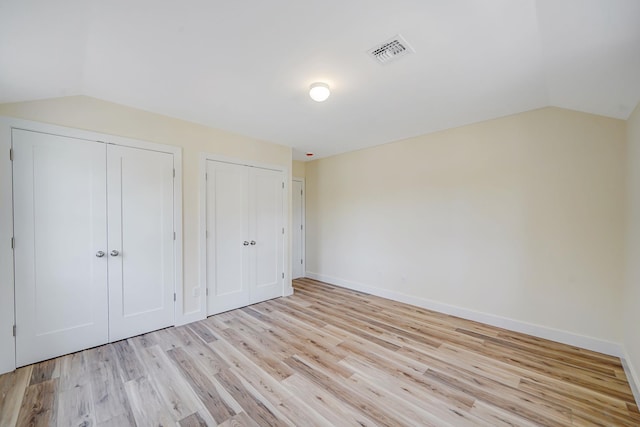 2939 N Wading River Rd, Wading River, NY 11792 - unfurnished bedroom with multiple closets, lofted ceiling, light wood-style floors, and baseboards