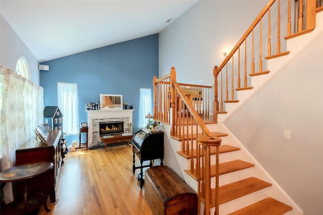 4 Pak Ct, East Setauket, NY 11733 - stairway featuring wood finished floors, high vaulted ceiling, and a glass covered fireplace
