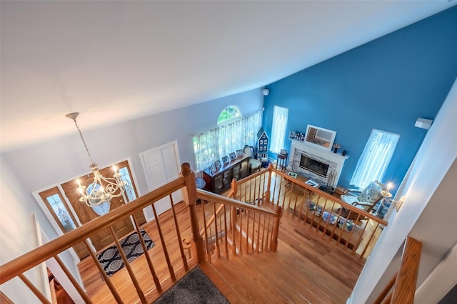 4 Pak Ct, East Setauket, NY 11733 - stairway with a chandelier, wood finished floors, lofted ceiling, and a glass covered fireplace