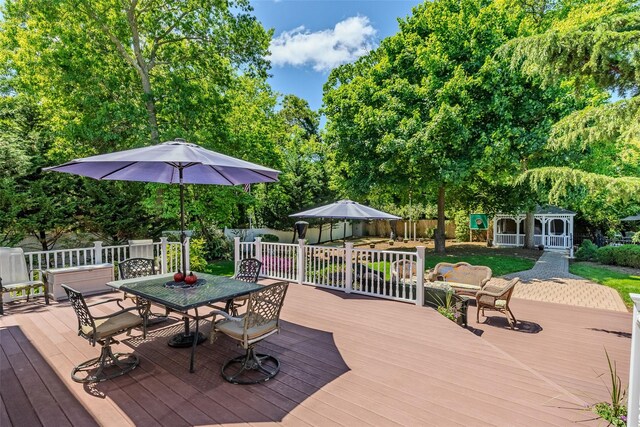 4 Pak Ct, East Setauket, NY 11733 - wooden terrace with outdoor dining area, an outbuilding, and view of wooded area