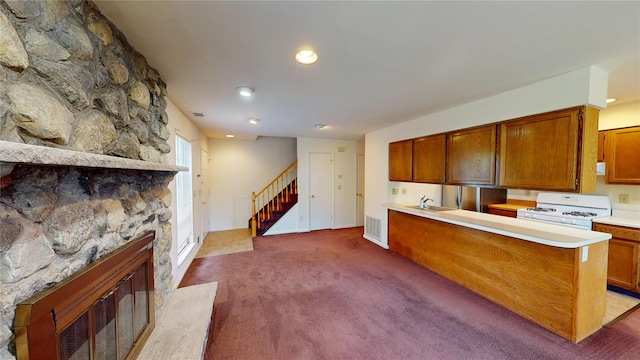 27 The Rise, Warwick, NY 10990 - kitchen featuring white gas range, a sink, carpet flooring, light countertops, and a fireplace
