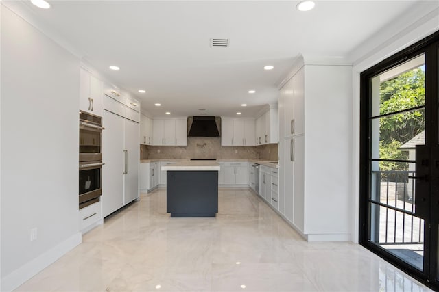 2 Henry St, Great Neck, NY 11023 - kitchen featuring wall chimney range hood, tasteful backsplash, a kitchen island, stainless steel double oven, and light countertops