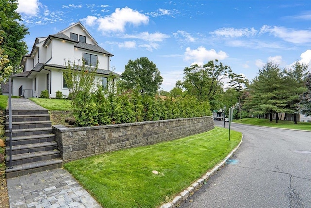 2 Henry St, Great Neck, NY 11023 - view of front of home featuring stucco siding, a front lawn, and stairs
