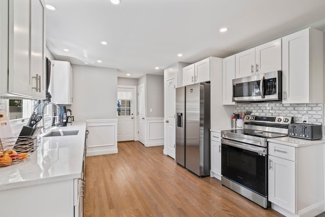 170 Lenox St, Port Jefferson Station, NY 11776 - kitchen featuring appliances with stainless steel finishes, a sink, white cabinetry, tasteful backsplash, and light wood-style floors
