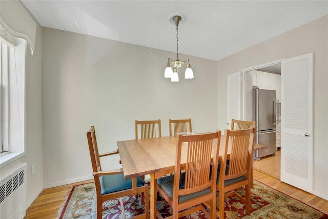 177 E Hartsdale Ave Unit 5L, Hartsdale, NY 10530 - dining area with a chandelier, radiator heating unit, and light wood finished floors