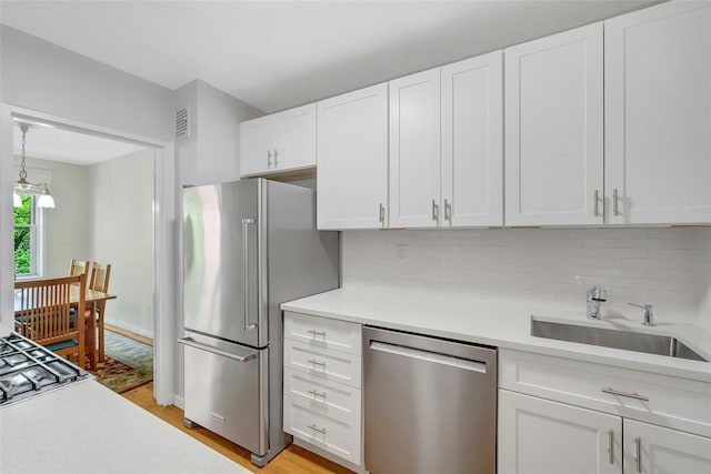 177 E Hartsdale Ave Unit 5L, Hartsdale, NY 10530 - kitchen featuring appliances with stainless steel finishes, light countertops, a sink, tasteful backsplash, and white cabinetry