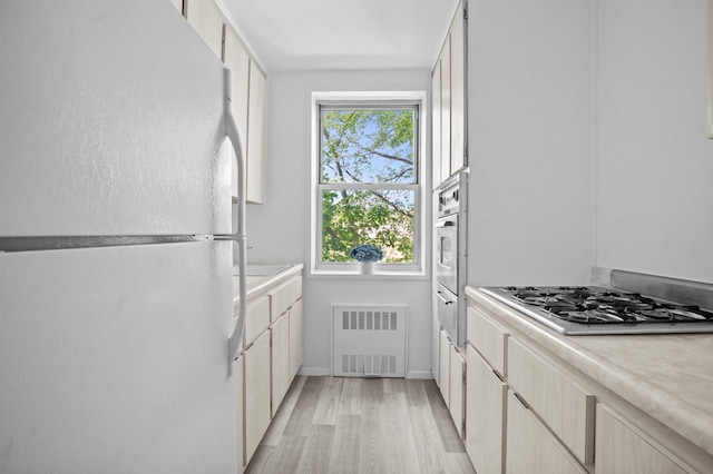 642 Locust St Unit 3K, Mount Vernon, NY 10552 - kitchen featuring freestanding refrigerator, radiator heating unit, stainless steel gas cooktop, light wood-style floors, and light countertops