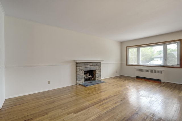 29 Newmarket Rd, Syosset, NY 11791 - unfurnished living room with radiator heating unit, wood finished floors, a stone fireplace, and baseboards