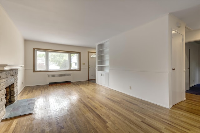 29 Newmarket Rd, Syosset, NY 11791 - unfurnished living room featuring radiator heating unit, wood finished floors, a fireplace, built in features, and baseboards