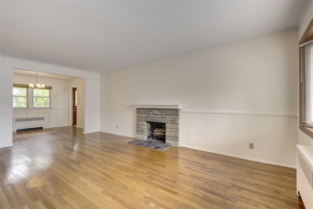 29 Newmarket Rd, Syosset, NY 11791 - unfurnished living room featuring radiator heating unit, a chandelier, wood finished floors, and a fireplace
