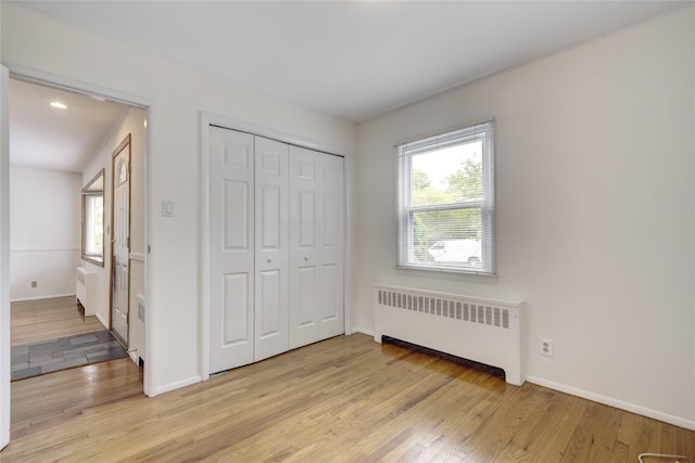 29 Newmarket Rd, Syosset, NY 11791 - unfurnished bedroom featuring radiator heating unit, light wood finished floors, baseboards, and a closet