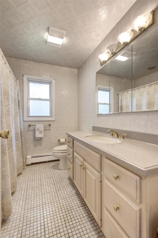 29 Newmarket Rd, Syosset, NY 11791 - full bath featuring a baseboard heating unit, tile walls, healthy amount of natural light, vanity, and toilet