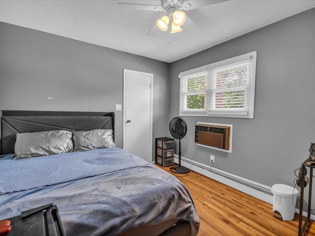 38 Nadine Ln, Port Jefferson Station, NY 11776 - bedroom featuring wood finished floors, a baseboard radiator, baseboards, ceiling fan, and a wall unit AC